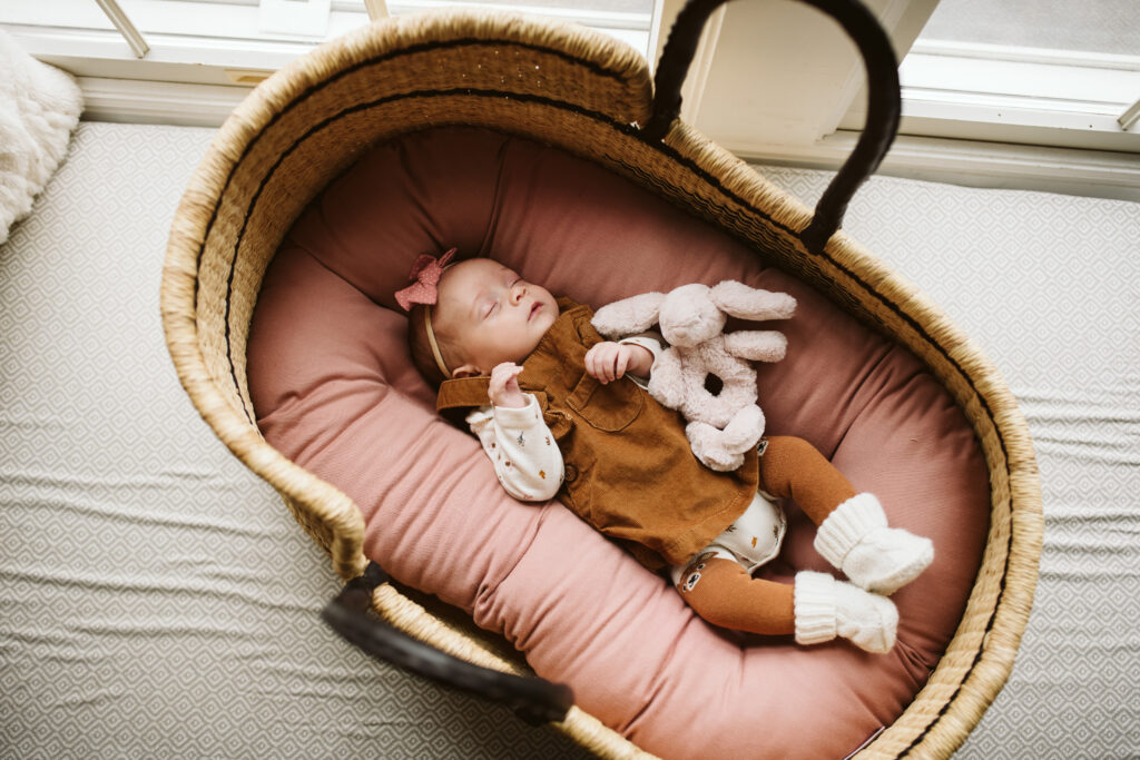 newborn baby resting in a basket on a window seat
