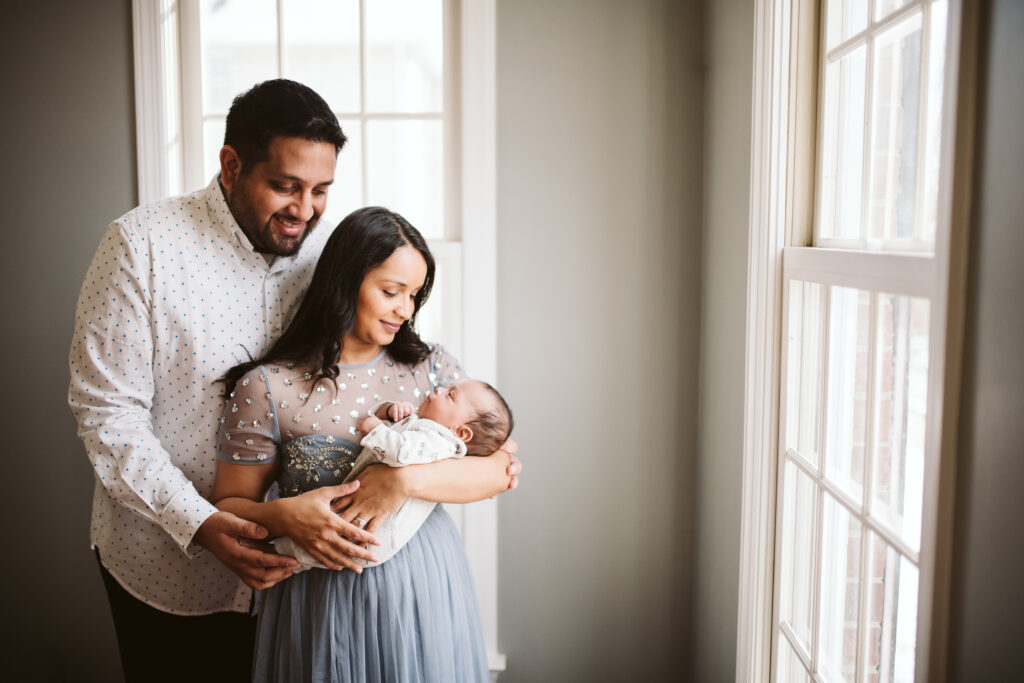 A couple holding their newborn baby. Lifestyle photo by Laura Mares Photography, Pittsburgh Newborn Photographer.