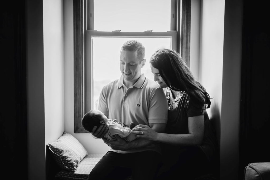 black and white portrait of parents admiring their newborn baby