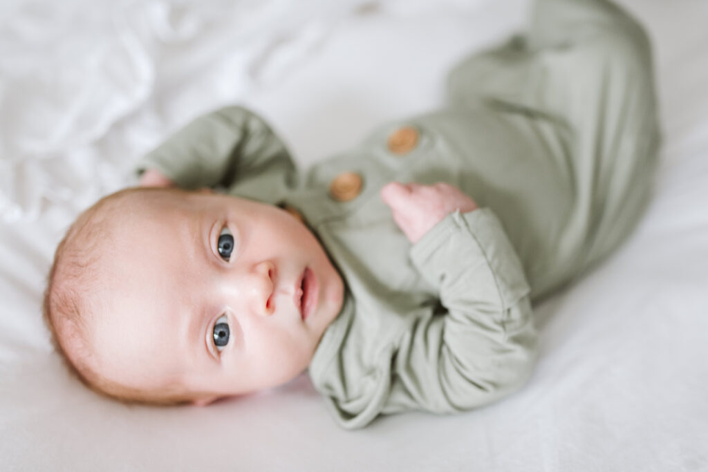 lifestyle photo of a newborn baby laying on a white bed