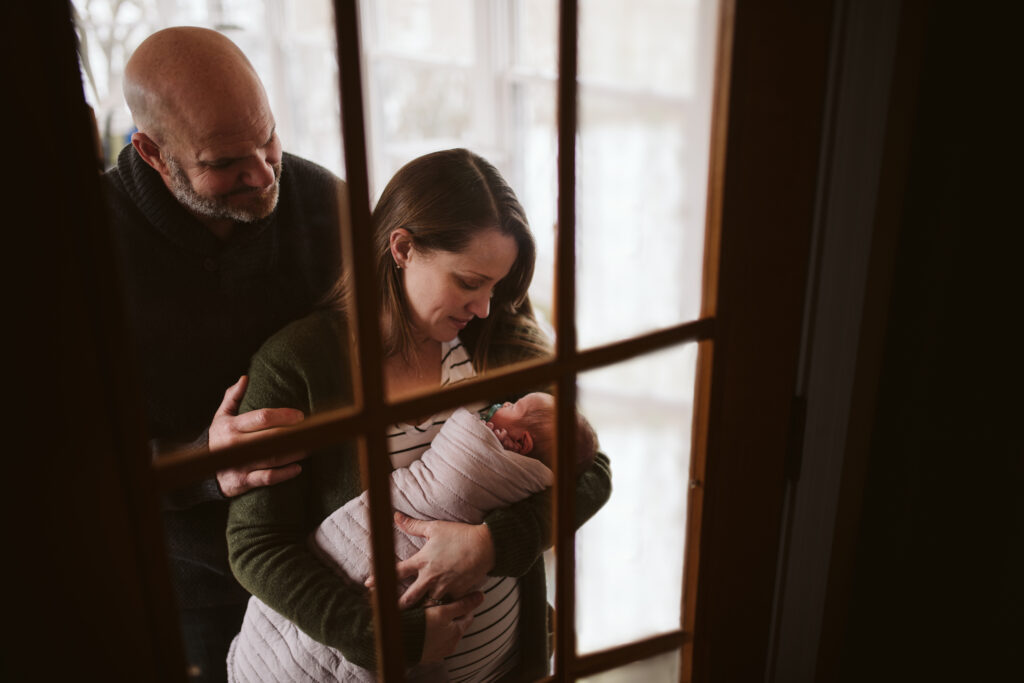 family holding newborn baby at home. Portrait taken by Laura Mares Photography, Pittsburgh Newborn Photographer