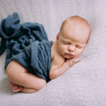 adorable newborn baby posed in a blue wrap in studio