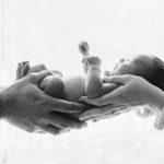 black and white newborn portrait in parents hands in studio