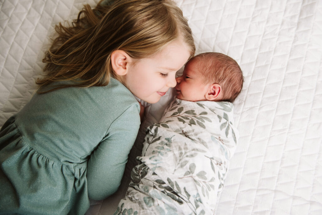 picture of big sister snuggling with newborn baby