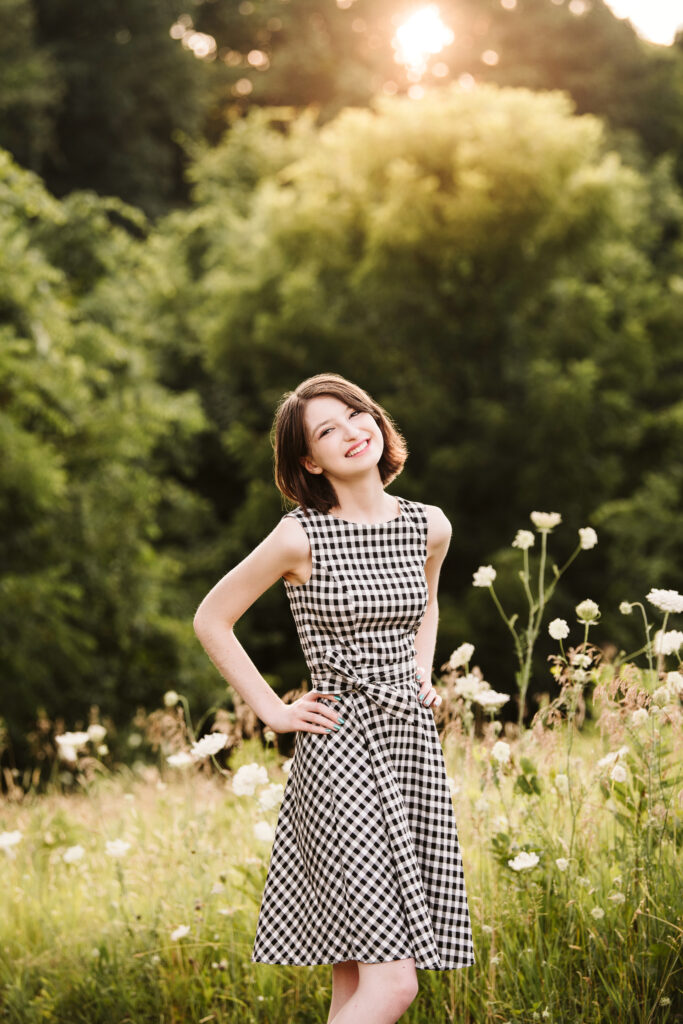 a senior girl smiling among wildflowers in the golden light of sunset