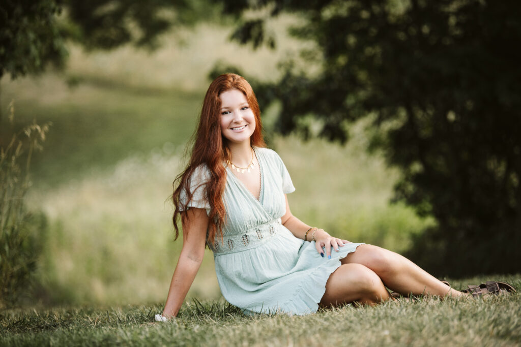 portrait of high school senior girl sitting on a green field