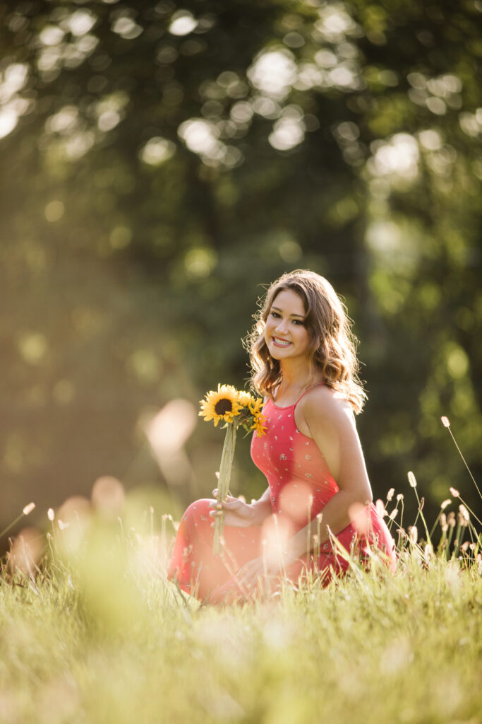 Portrait of a senior girl sitting on a field at sunset. Photo by Laura Mares Photography, Pittsburgh Senior Photographer