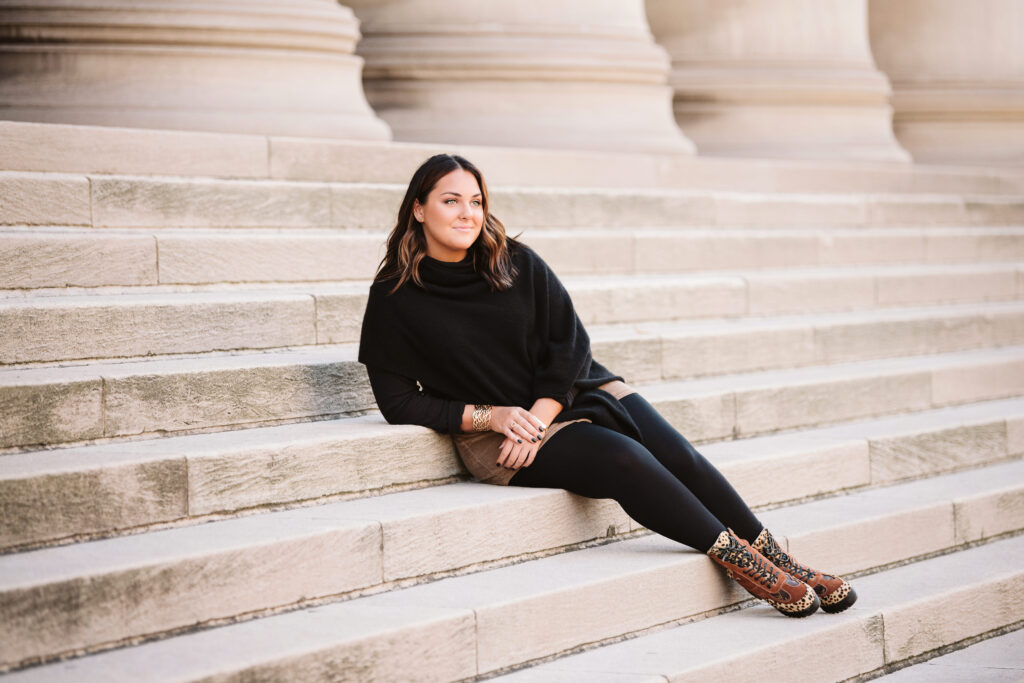 senior girl wear black and poses on marble steps