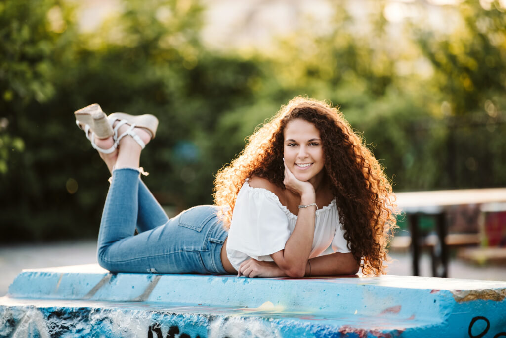 portrait of a high school senior girl laying down in Pittsburgh's Color Park at sunset