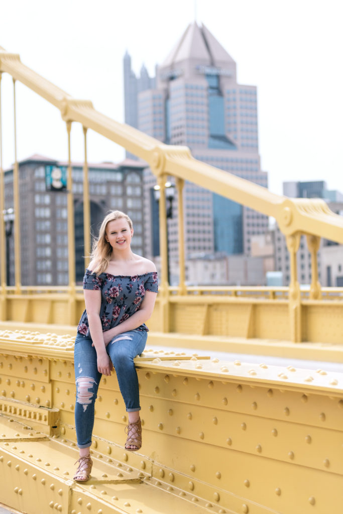 senior girl sitting on the Roberto Clemente Bridge near on the North Shore of Pittsburgh, photographed by Pittsburgh Photographer, Laura Mares Photography