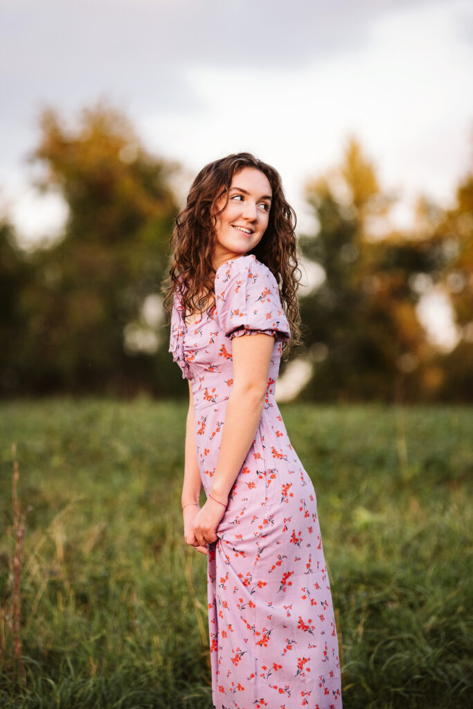 senior girl dances in a field during senior photo session