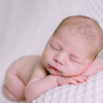 newborn sleeping on a white blanket photographed by Laura Mares a pittsburgh newborn photographer