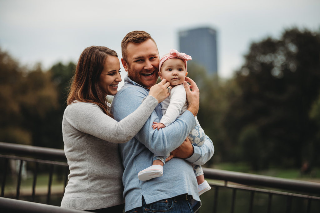 Causal portrait of a family of three enjoying each other in a park. Photograph by Laura Mares Photography, Pittsburgh Family Photographer.