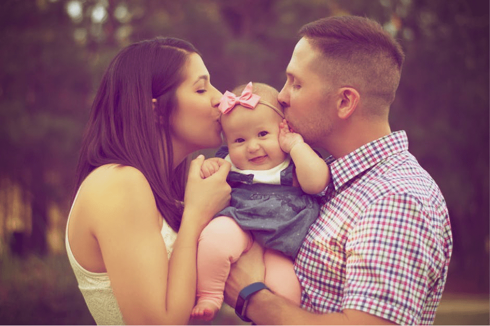 mother and father kissing their baby daughter