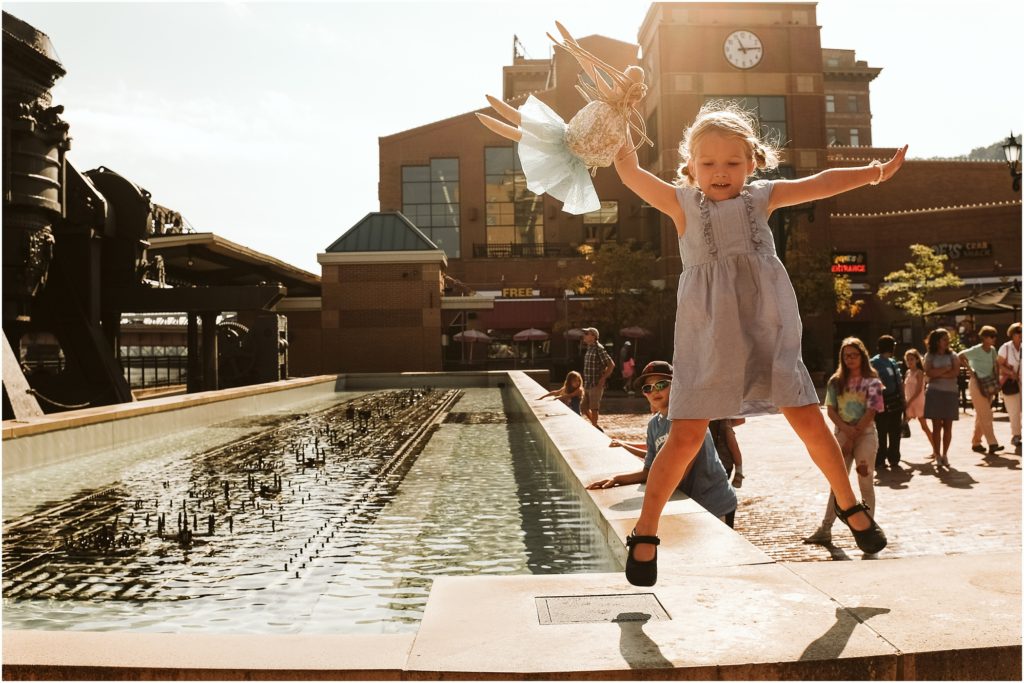 Girl jumping on the fountain at Station Square. Photo by Laura Mares Photography, Pittsburgh Child Photographer.