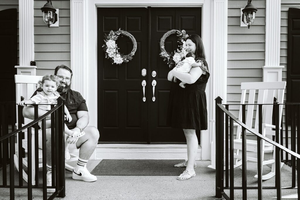 black and white image of family on front porch durning newborn lifestyle session