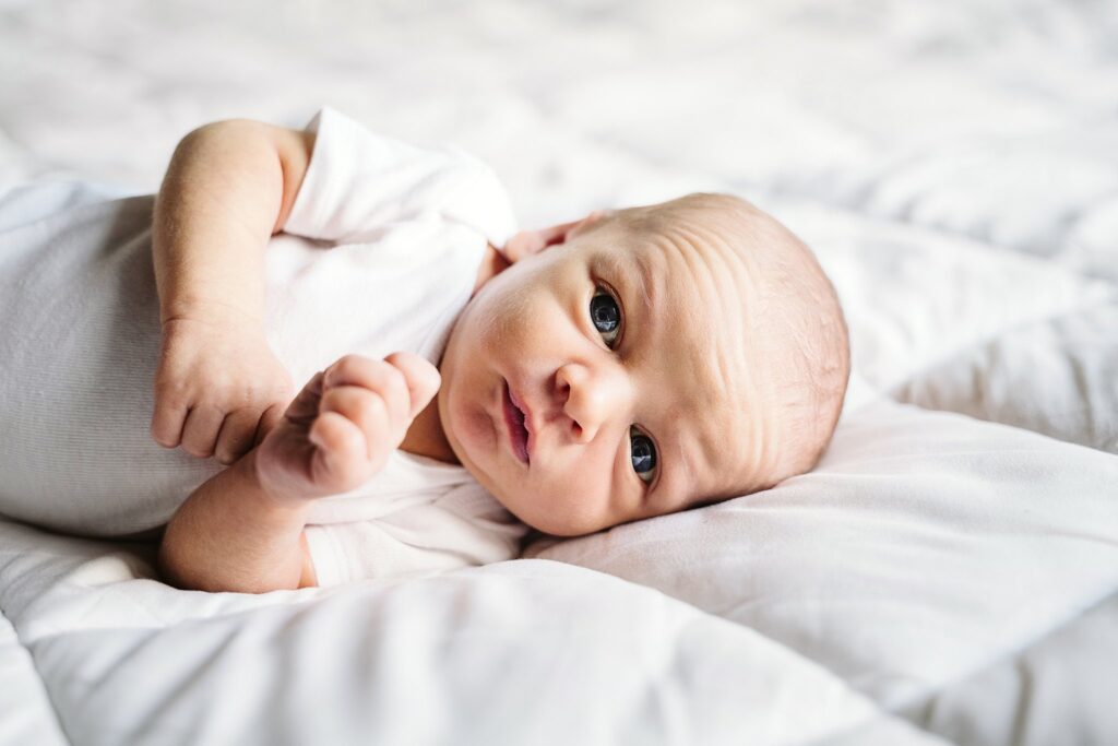 natural portrait of newborn baby laying on white bed in white studio