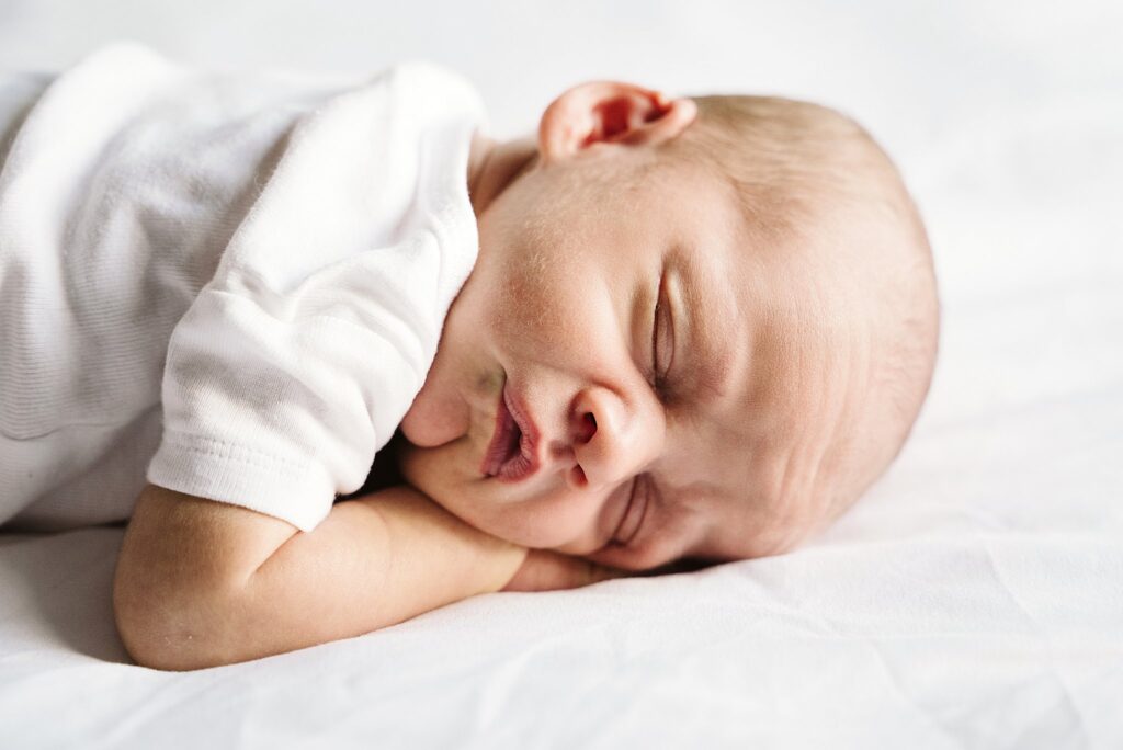 natural portrait of newborn baby laying on white bed in white studio