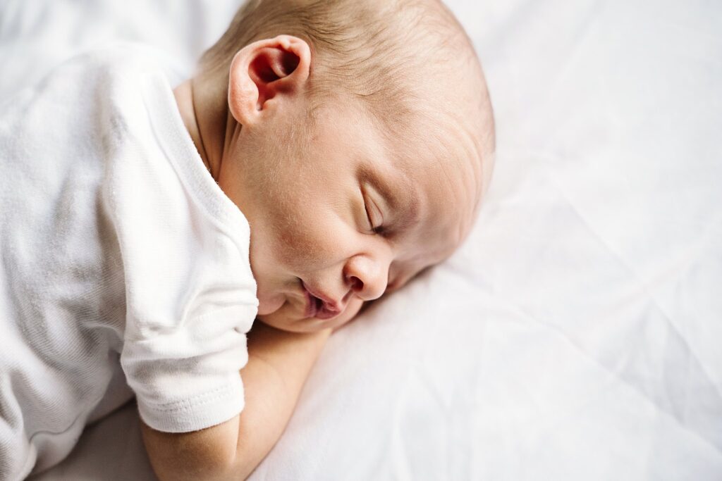 natural portrait of newborn baby laying on white bed in white studio