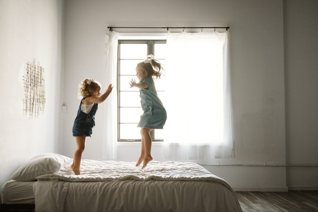 lifestyle portrait of young girls jumping on a bed