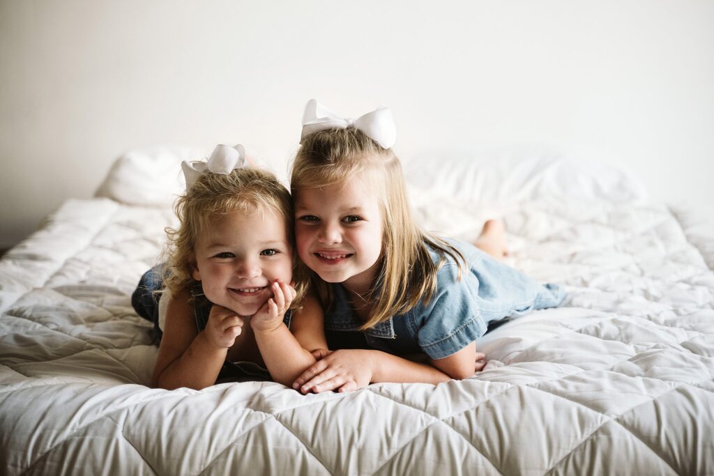 lifestyle portrait of young girls laying on a bed