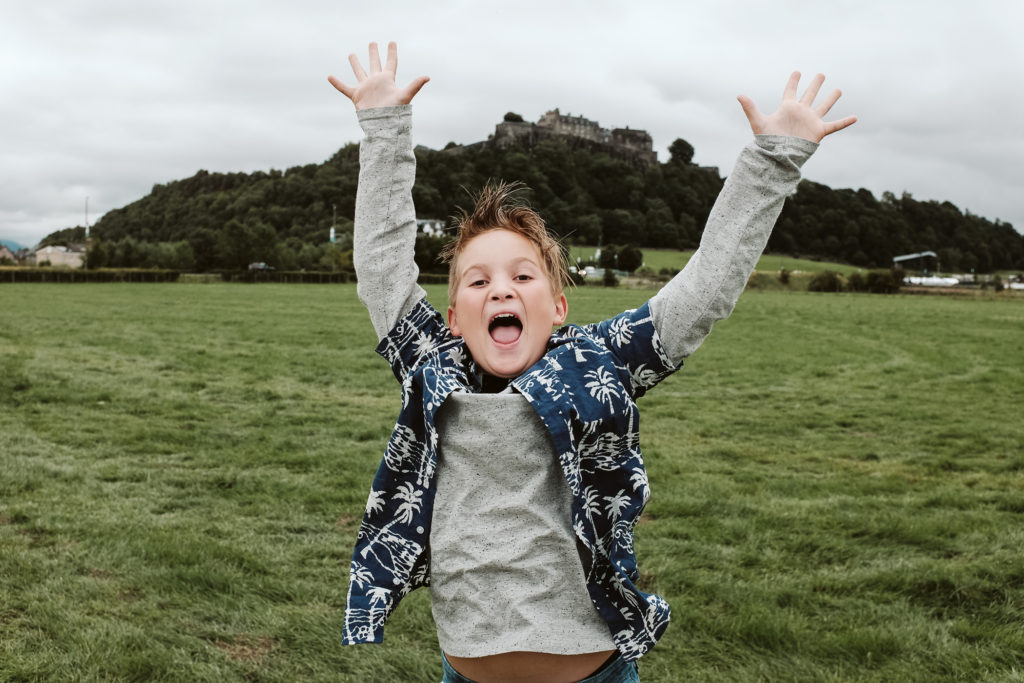 Boy jumping for joy near Stirling Castle in Scotland. Photograph by Laura Mares Photography.
