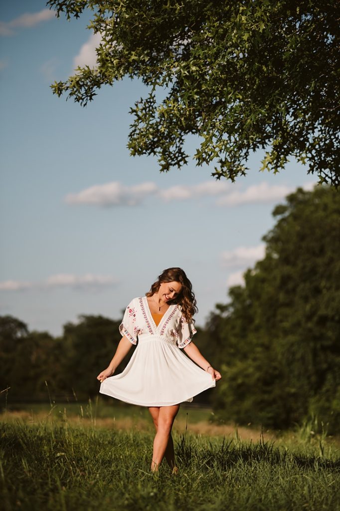 Portrait of a high school senior girl dancing on a rustic field at sunset. Photo by Laura Mares Photography, Pittsburgh Senior Photographer.