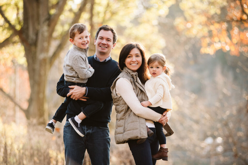 a family of four posing for a fall family photo