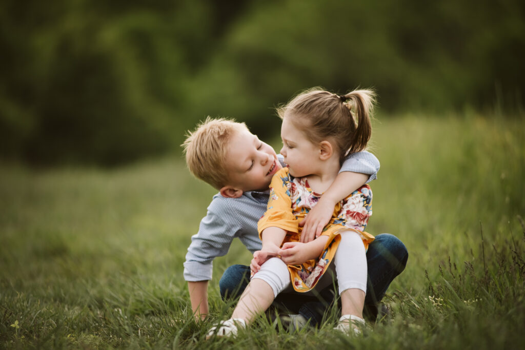 brother and sister talking in a free field at sunset