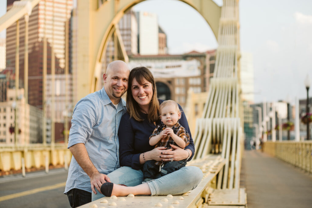 a family of three sitting on a yellow bridge at sunset