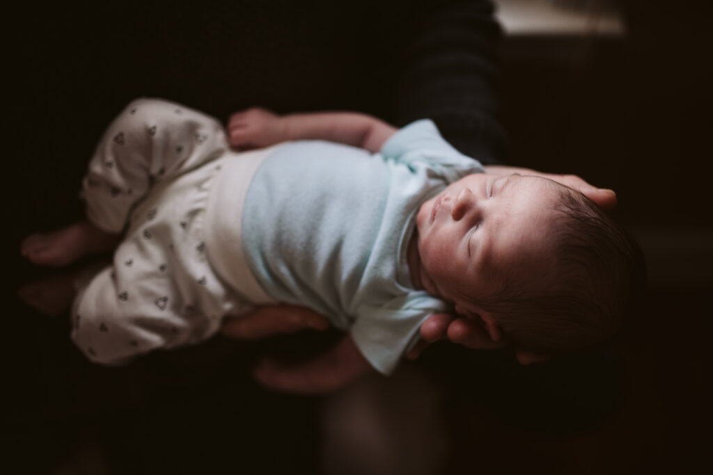 a sleeping baby girl held in her father's hands