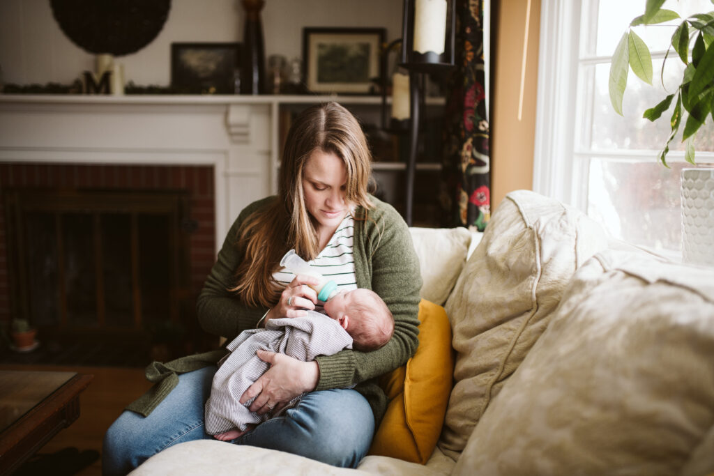 a new mom bottle feeding her newborn baby in the living room