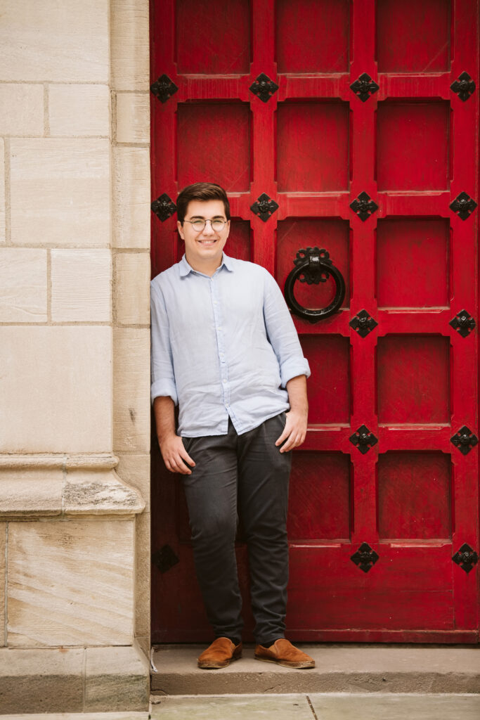 A senior guy leaning on a red door in Oakland.