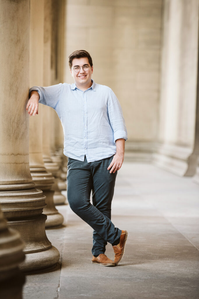 Portrait of a high school senior guy learning against columns in Pittsburgh