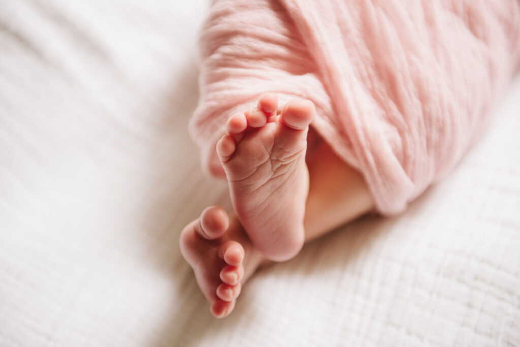 newborn baby toes wrapped in a pink swaddle
