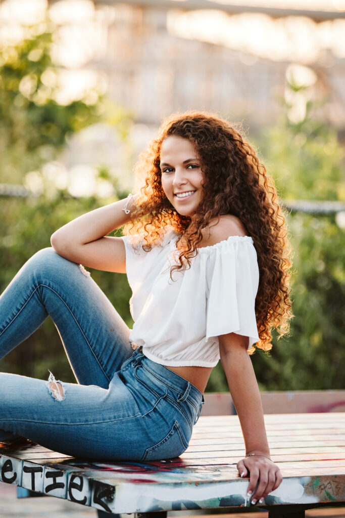 portrait of a high school senior girl sitting on a picnic table in Pittsburgh's Color Park during sunset