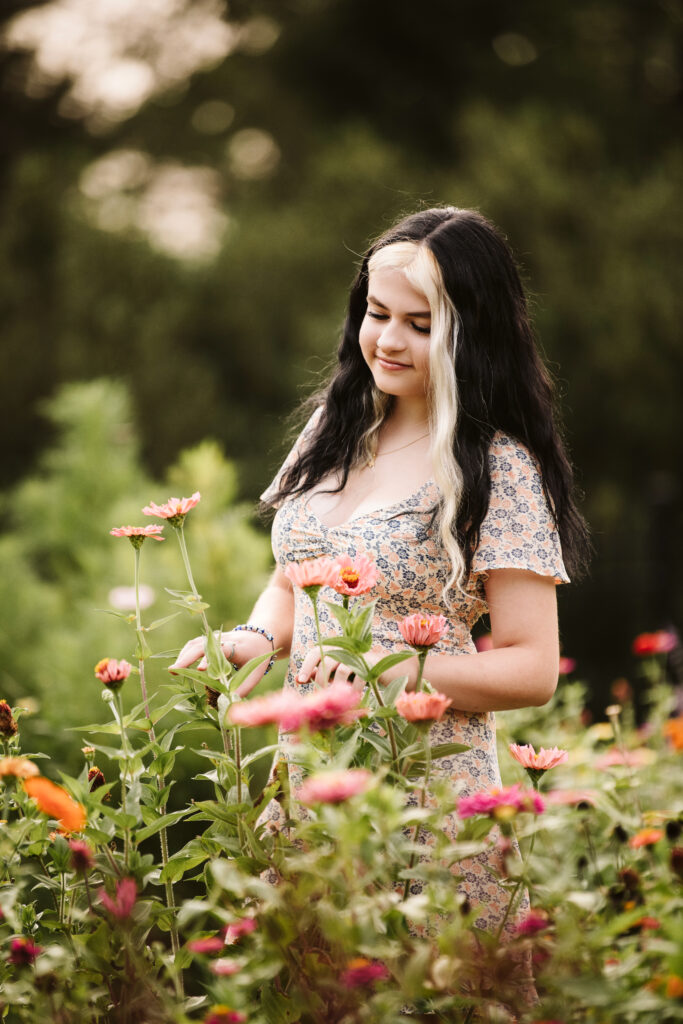 portrait of a high school senior girl admiring beautiful flowers in a garden at Hartwood Acres