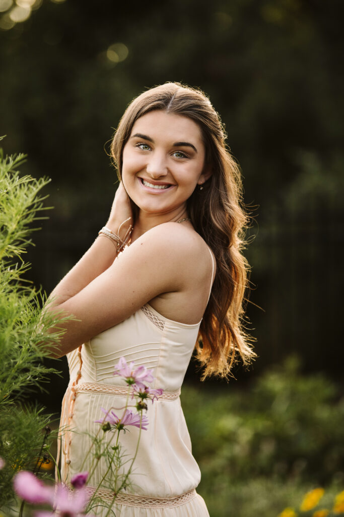 senior portrait of a girl playing with her hair in a flower garden during golden hour at Hartwood Acres