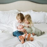 Lifestyle picture of siblings holding baby brother in their arms