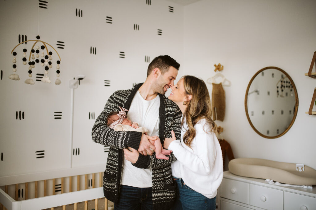 loving parents holding newborn in modern bohemian nursery