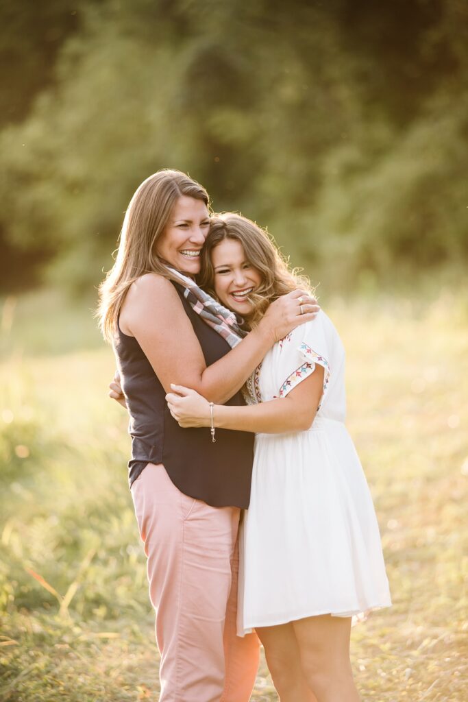 high school senior photo with a senior girl hugging her mom in a rustic field at sunset