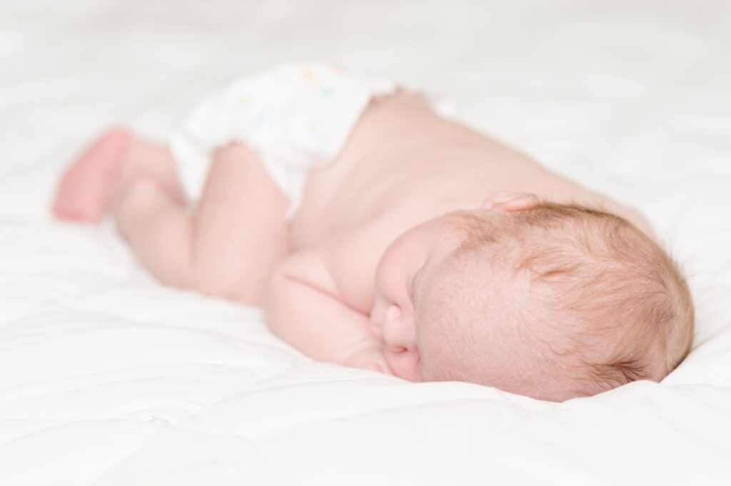 simple white studio newborn portrait featuring baby's hair pattern