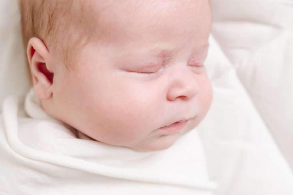 simple white studio newborn portrait featuring baby's eye lashes