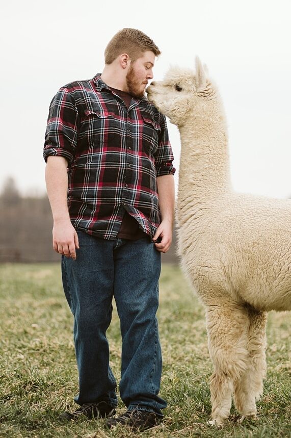 A portrait of a senior guy up close with an alpaca near Pittsburgh. Portrait by Laura Mares Photography, Pittsburgh Senior Photographer