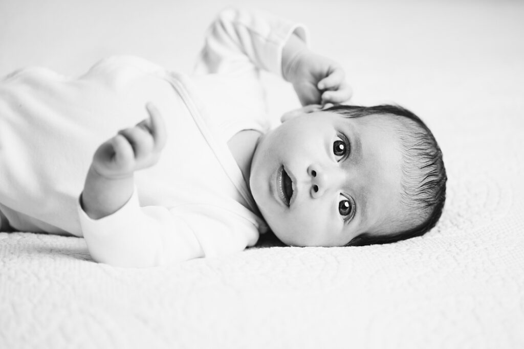 black and white portrait of happy newborn baby laying on bed