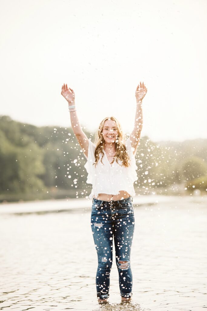 Senior girl splashing in water at sunset near Pittsburgh