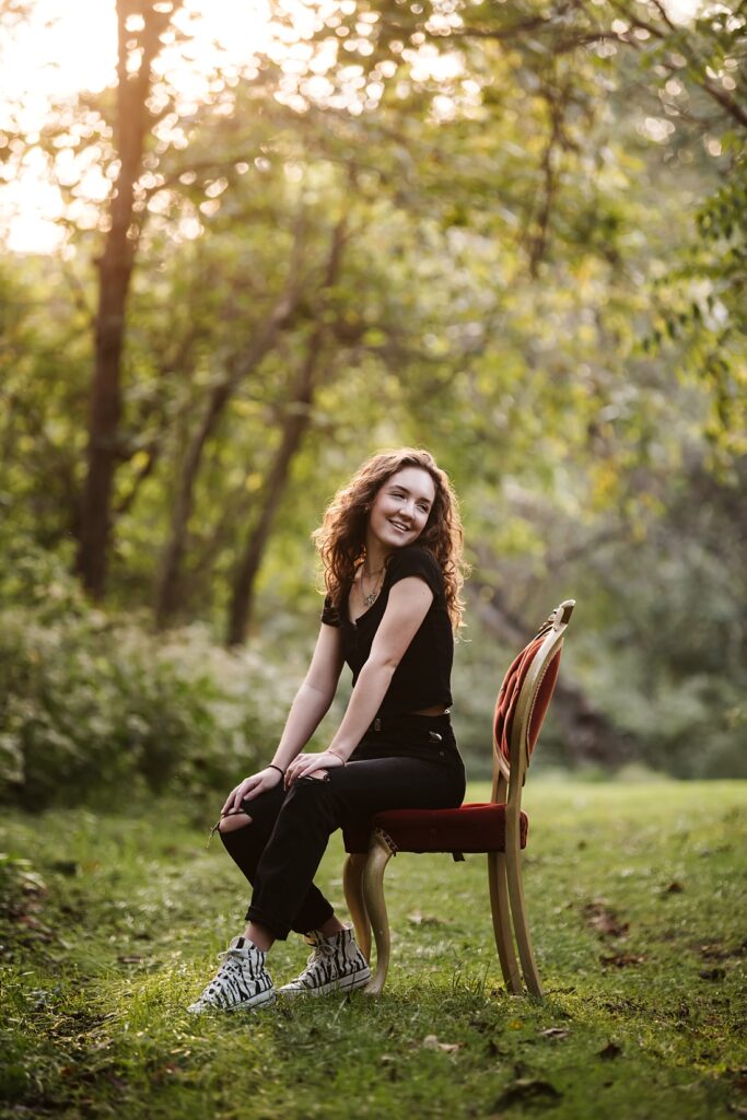 senior girl sitting on a vintage chair in the forest