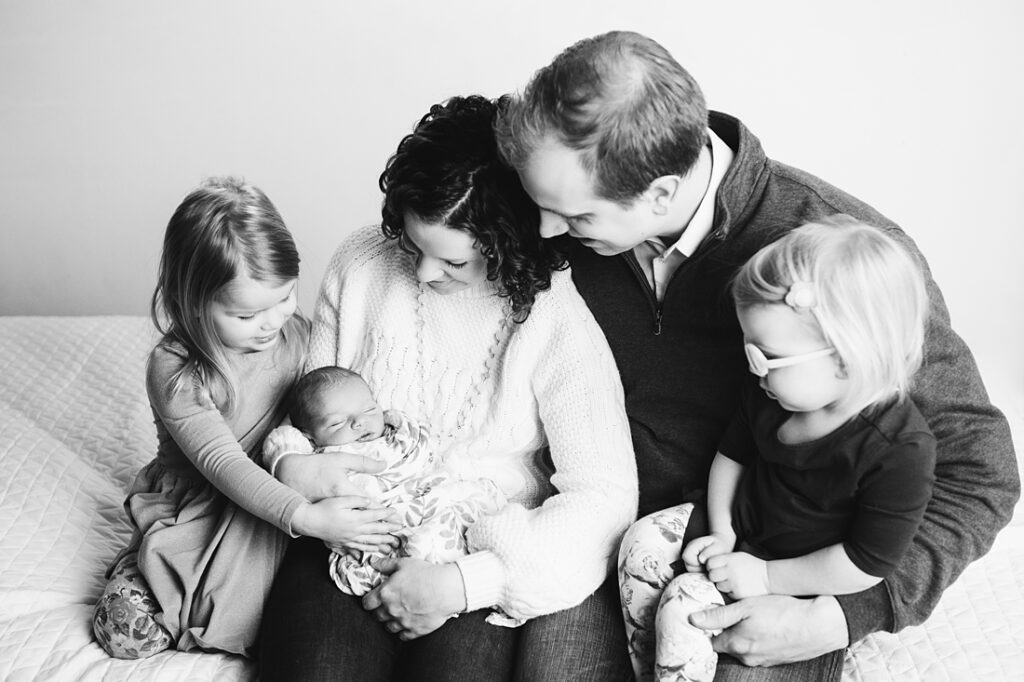 black and white portrait of newborn baby with family in studio