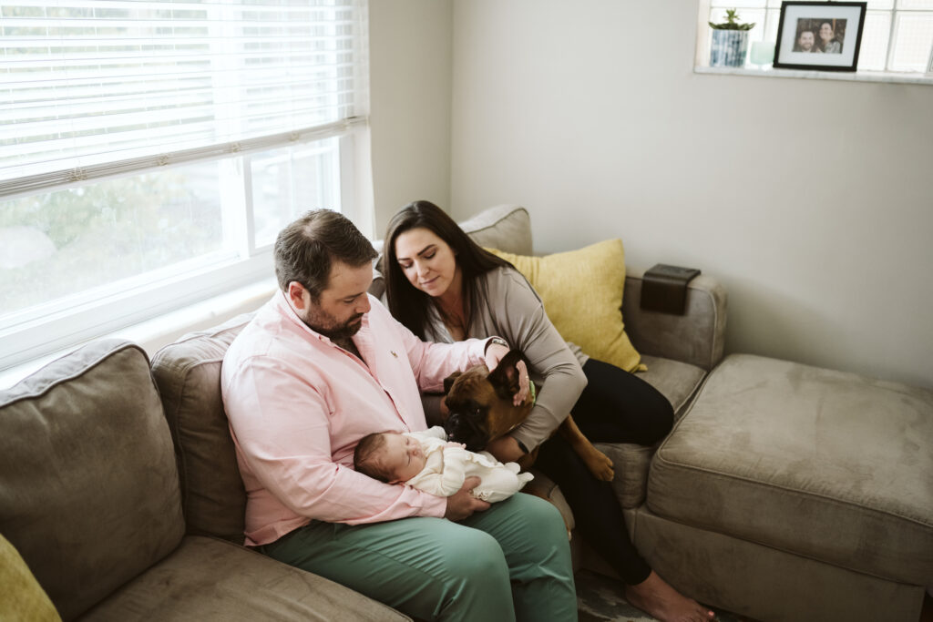 newborn lifestyle picture of family holding baby in living room
