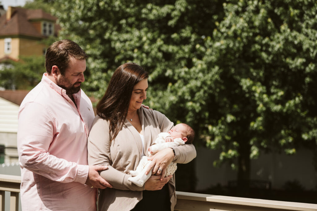 newborn lifestyle picture of family holding baby outside